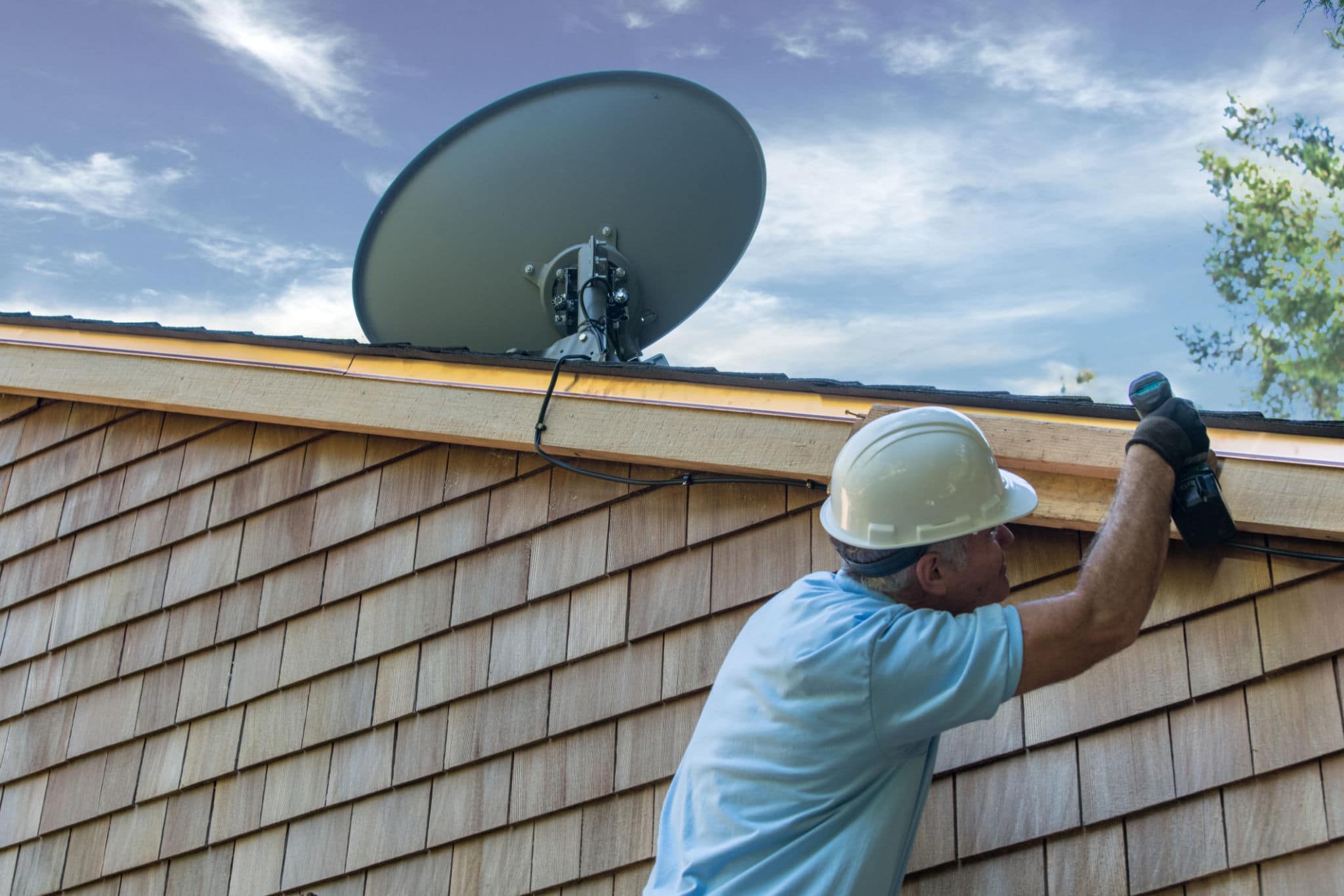 Man installing Satellite Dish on roof of  house